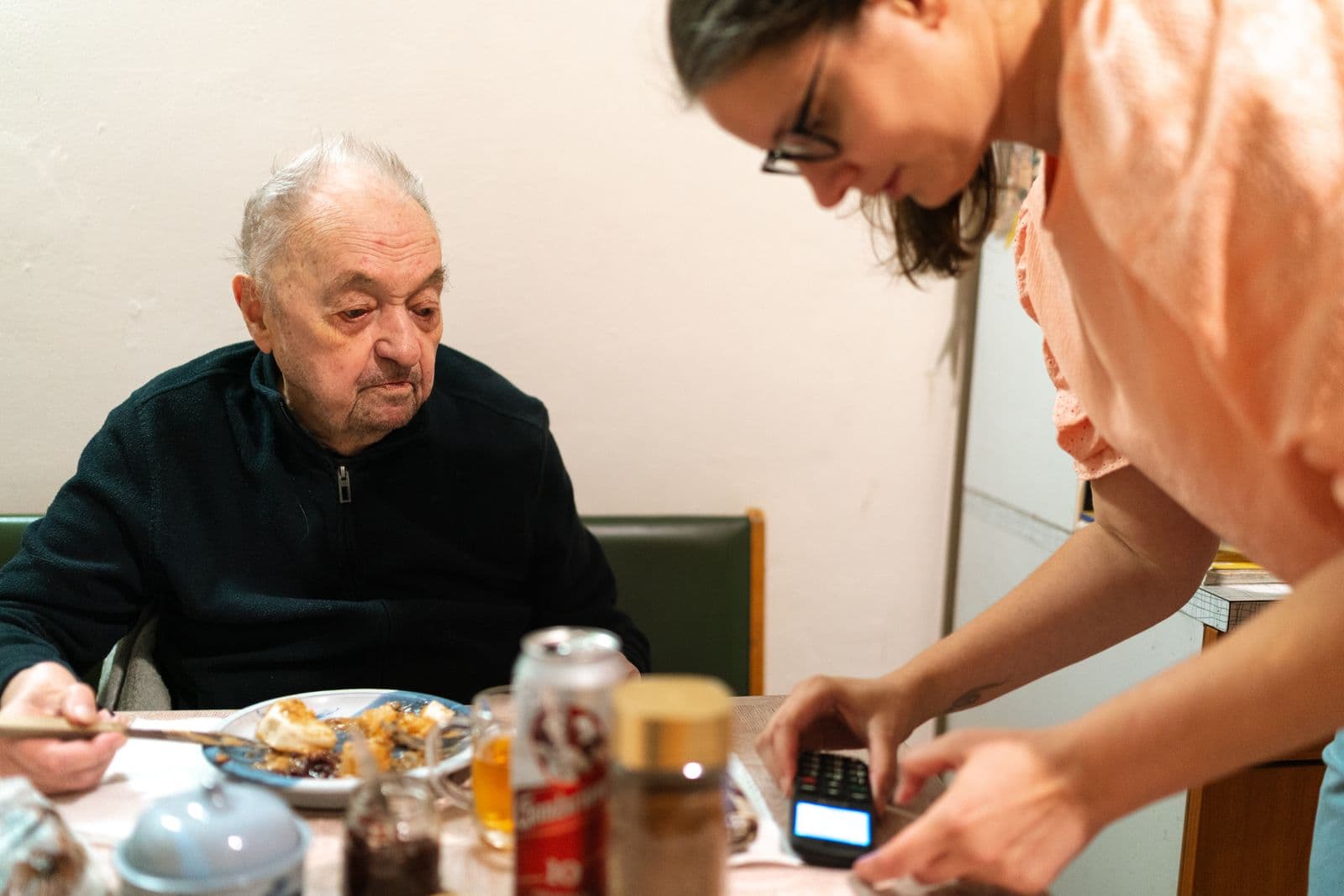Caregiver serving lunch to an older man at the table